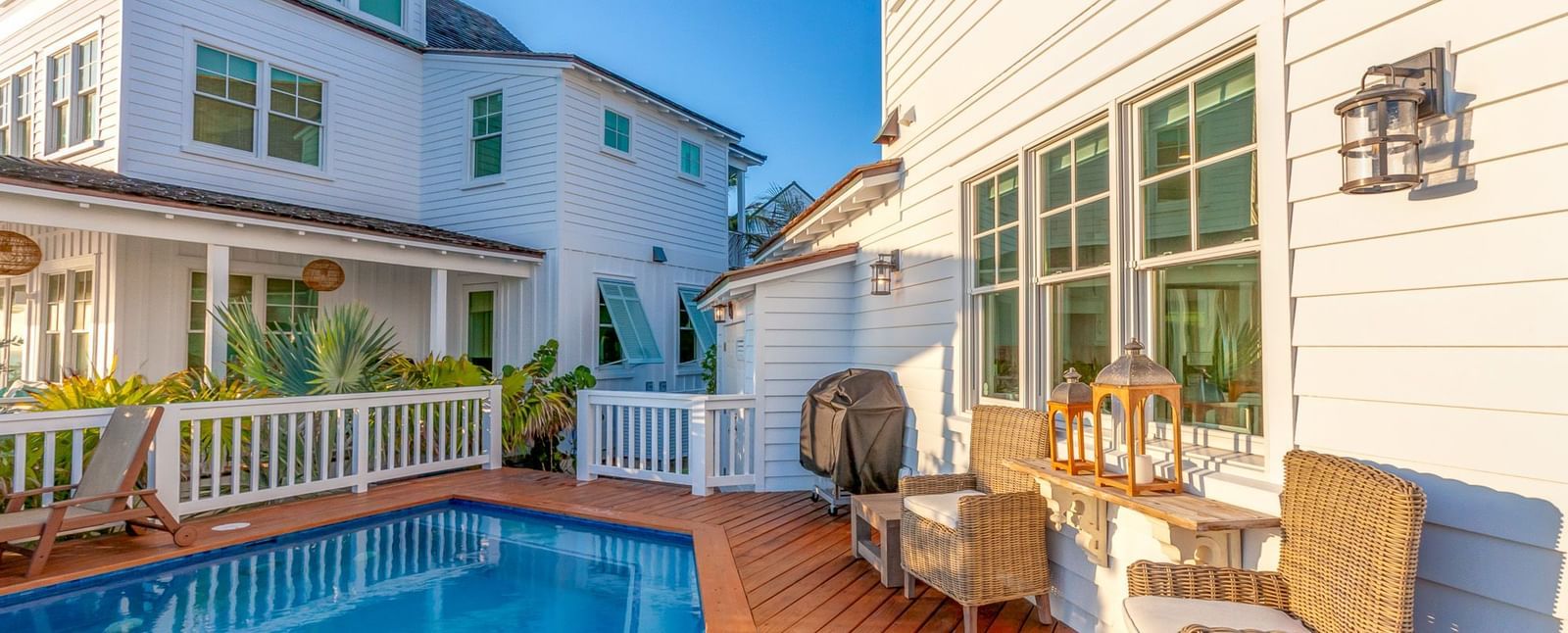 a swimming pool and two houses on a dock with wooden chairs at Abaco Inn.