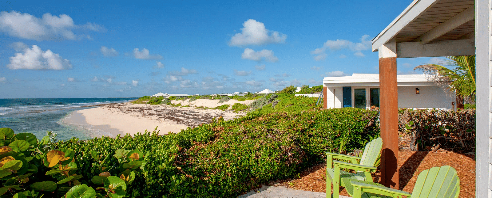 Patio with green chairs facing the ocean and coastal vegetation | Abaco Inn