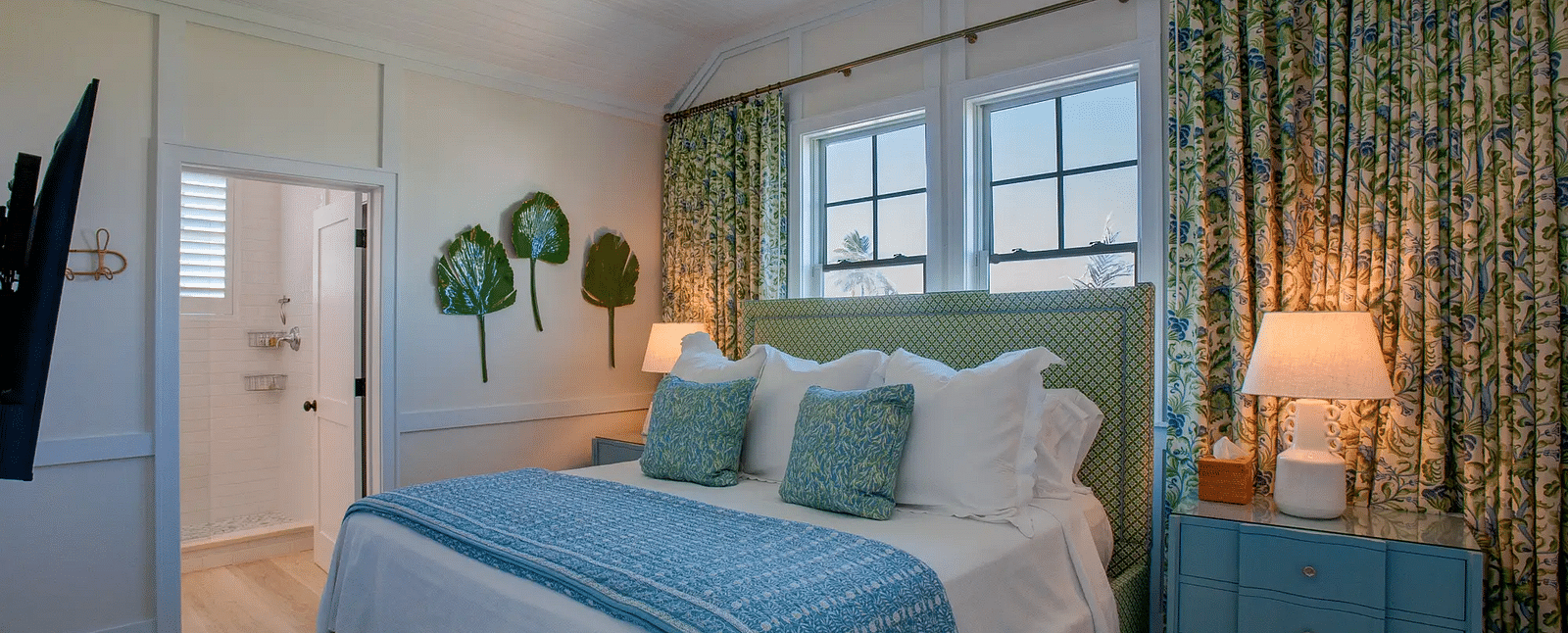 Bedroom with green floral curtains, a blue dresser, and white bedding | Abaco Inn