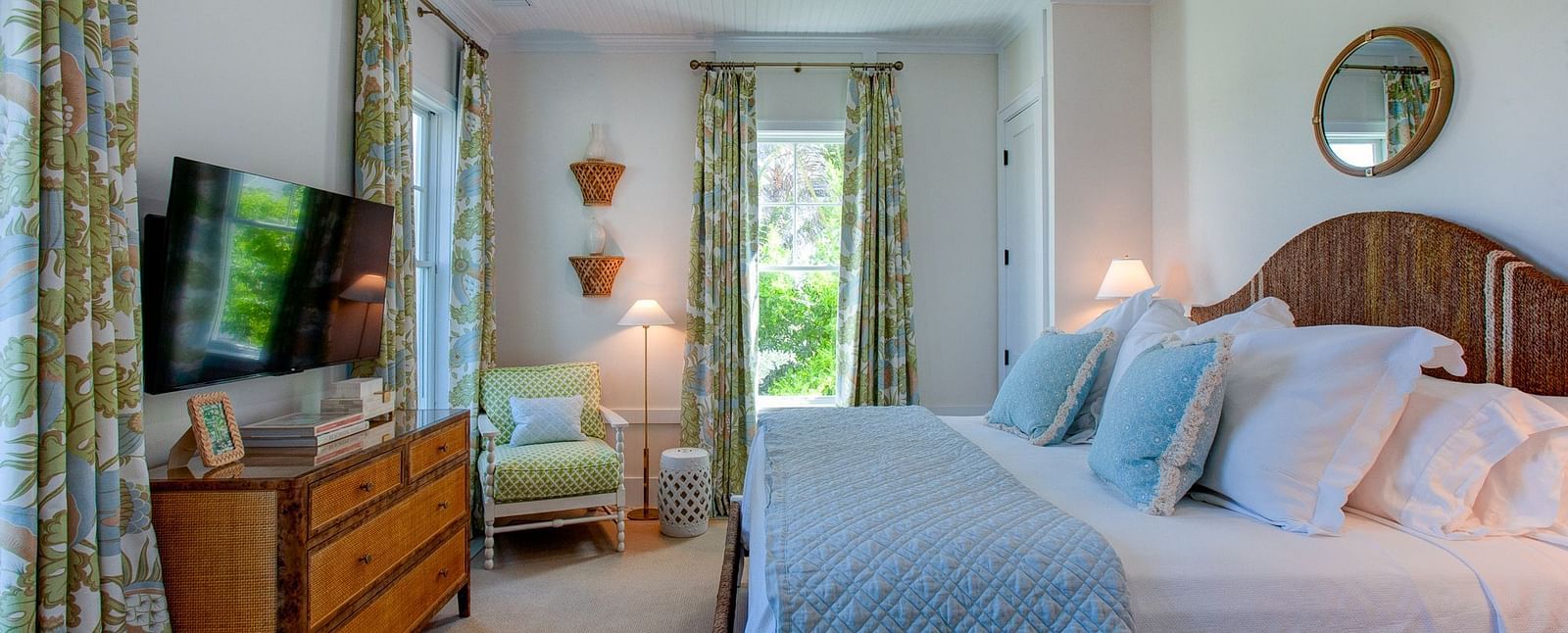 A well-appointed bedroom at Abaco Inn featuring a large bed featuring a headboard, bedside tables with lamps, and a television mounted on a dresser 