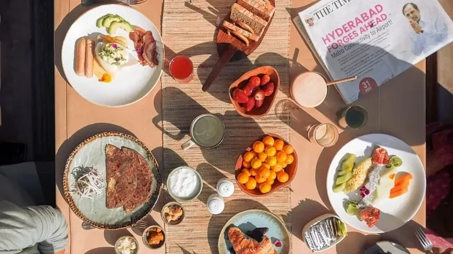 Overhead view of a wooden table filled with various dishes and drinks at Karma Chalets.