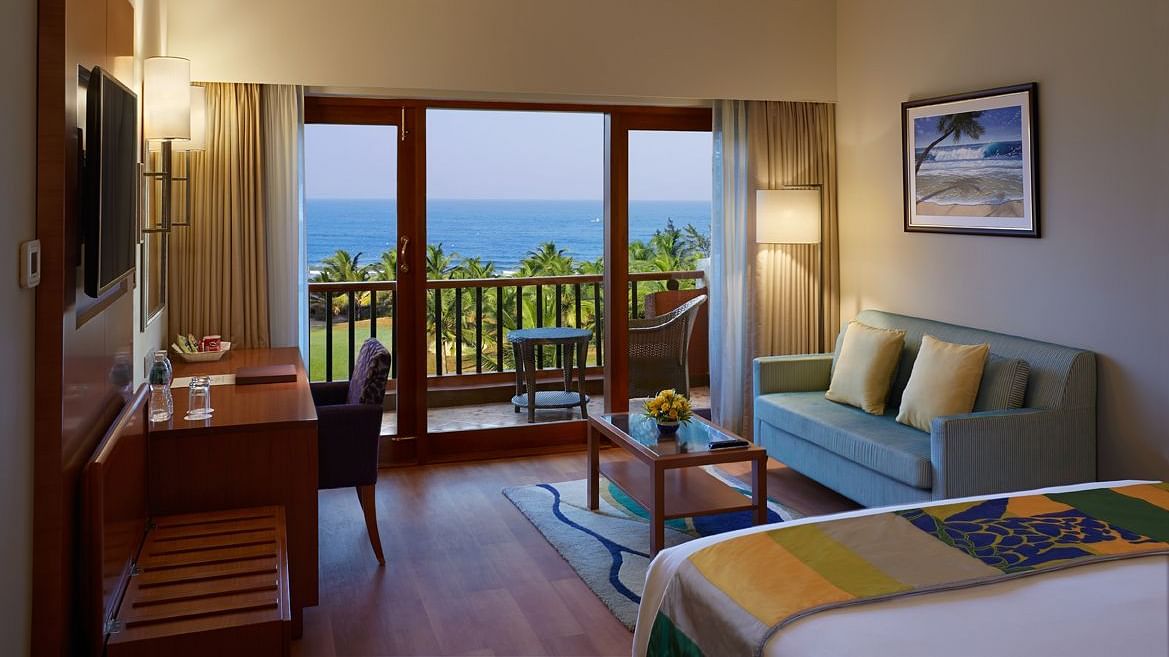 a double bed with a sofa, table, lamps and tv in view inside Ocean front view - Caravela Beach Resort Goa