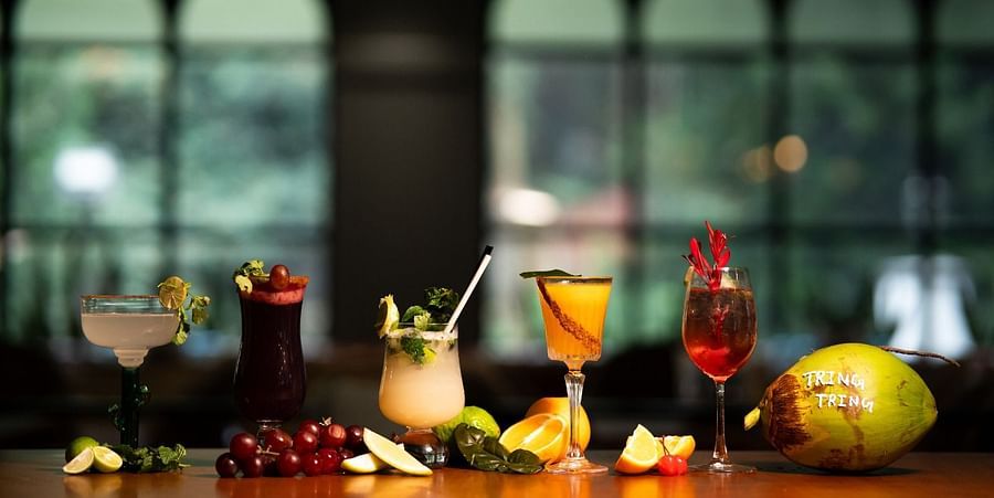 alt-text An image showcasing a variety of mocktails, cocktails, and fresh fruits arranged on a wooden counter.