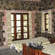 A spacious rustic cabin bedroom featuring Exposed stone and brick walls, wooden twin beds, and large windows with patterned curtains.