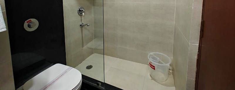 A bathroom featuring a full size bathtub along with a commode separates by a glass partition in the Suite - Hotel Gold, Panipat