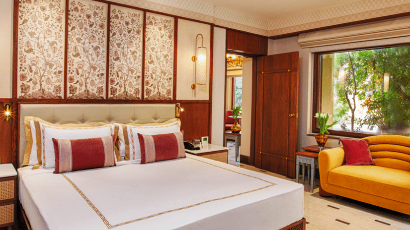 Room with double bed, cushioned seating, and decorative wall panels at Heritage Village Resorts & Spa, Manesar.