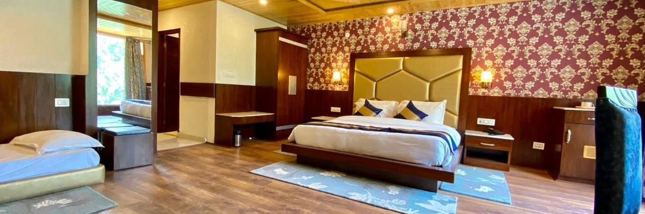 A spacious room at La Serene Valley, Manali, with a king sized bed, seating area, and large windows inviting natural light.
