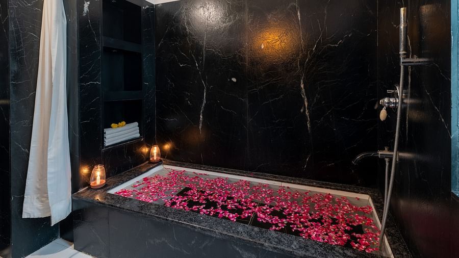 A spacious bathtub filled with water and scattered flower petals at Panna Vilas Palace