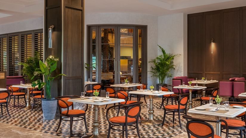 Corner view of the Carnaby dining area at The Residency Towers Chennai, featuring warm ambiance, arranged tables, chairs, and indoor plants.
