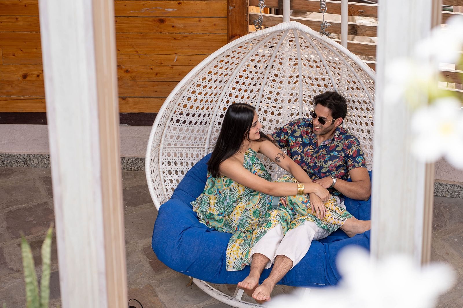 Two people sitting in a hanging chair or swing.
