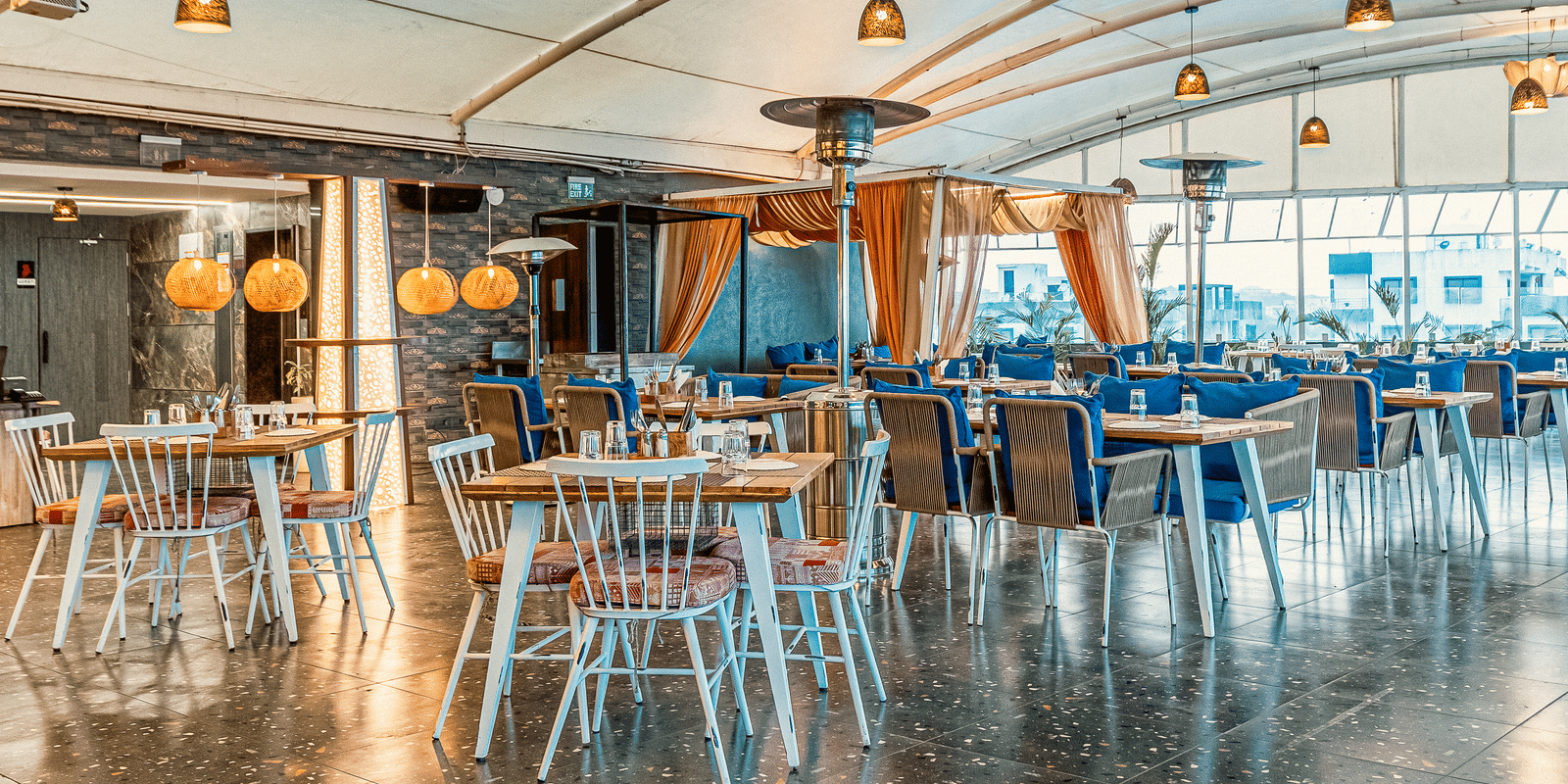 Stylish interior of The Papaya Tree Hotel’s Nazara restaurant showcasing golden ceiling decor, artistic chandeliers, and neatly arranged dining tables in a contemporary setting.