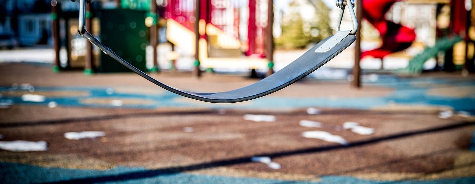 A close-up image of a single swing, with the surrounding environment softly blurred. The swing is prominently featured.