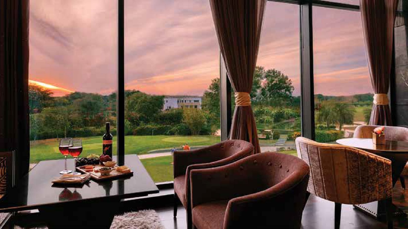 Seating arrangements inside a restaurant with the lawn area seen through the window - Karma Lakelands.