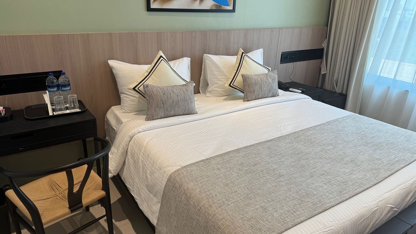 A king bed with side tables and a study chair next to it inside deluxe room - Hotel Mumbai House, Valnai, Malad
