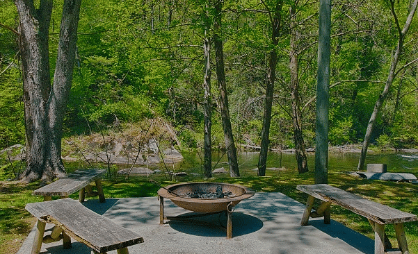 a fire pit surrounded by several wooden chairs in a garden and tall green trees - Historic Tapoco Lodge