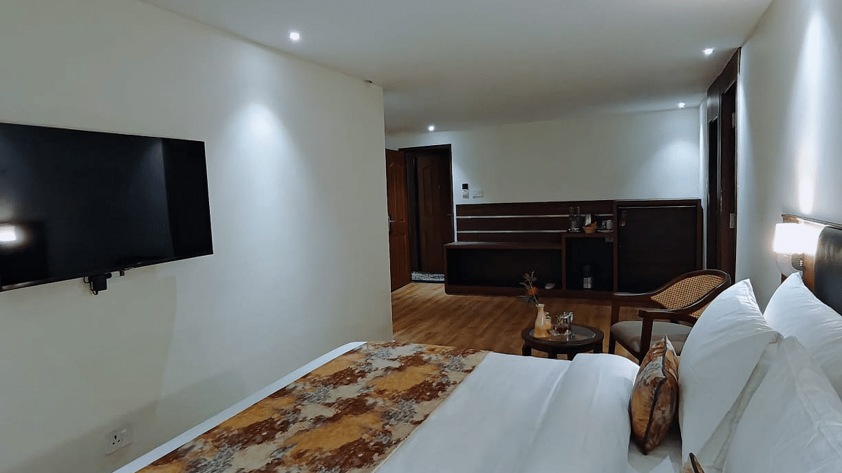 A close-up shot of a  bed with patterned runner opposite to which a tv is mounted on the wall - Sumitel JB Park, Darjeeling
