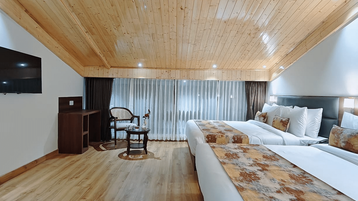 A hotel room with two beds and patterned runners, a tv on the wall and a hallway view, showing the room's layout - Sumitel JB Park, Darjeeling