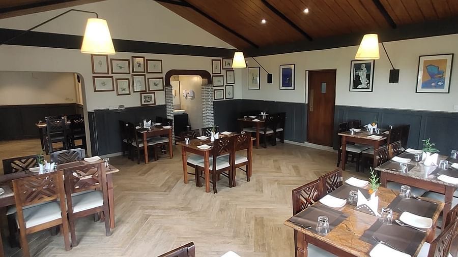 Interior of a restaurant with wooden tables, chairs, and a high ceiling.