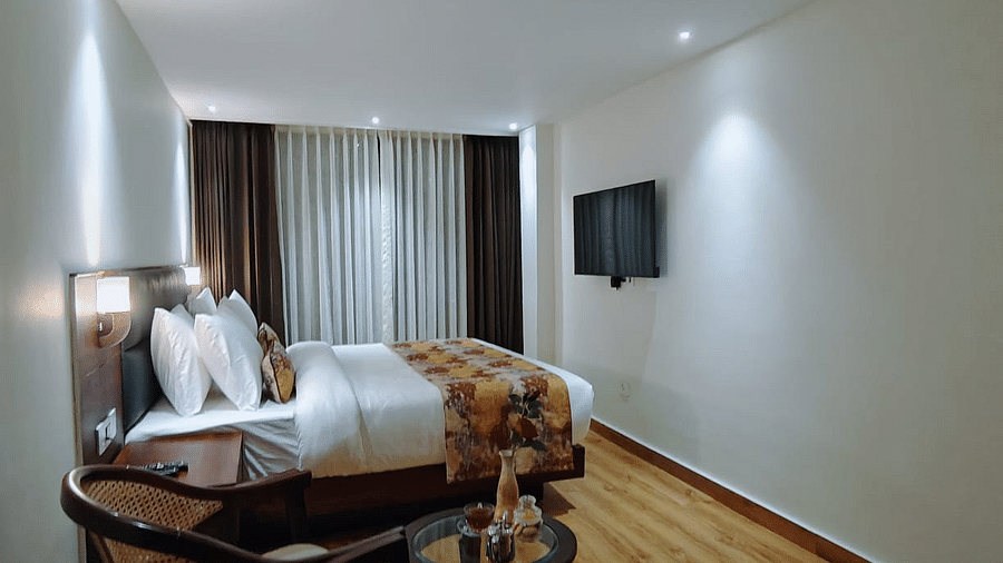A close-up shot of a chair and a bed with patterned runner, showcasing a room's amenities - Sumitel JB Park, Darjeeling