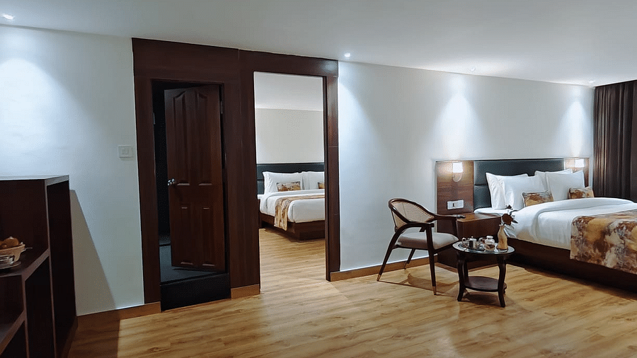 A view of a room with a bed and chair kept beside it in a warm lighting - Sumitel JB Park, Darjeeling