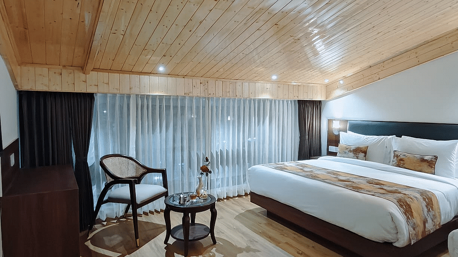 A room in Darjeeling with a bed, a chair, and a wood ceiling, providing a glimpse of the room's ambience and layout - Sumitel JB Park, Darjeeling