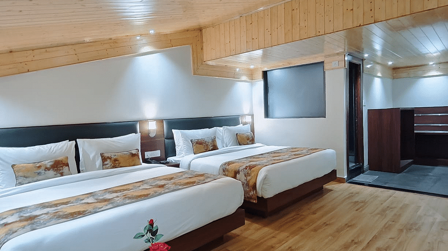 A hotel room with two beds, a side table and a wood ceiling highlighting the room's design and furnishings - Sumitel JB Park, Darjeeling
