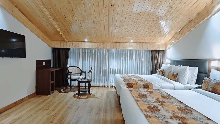 A hotel room with two beds and patterned runners, a tv on the wall and a hallway view, showing the room's layout - Sumitel JB Park, Darjeeling