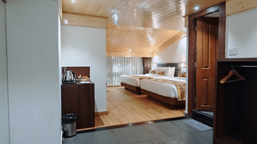 A hotel room with a hallway view, showing a bed with white linens and a decorative runner, leading into the main space - Sumitel JB Park, Darjeeling