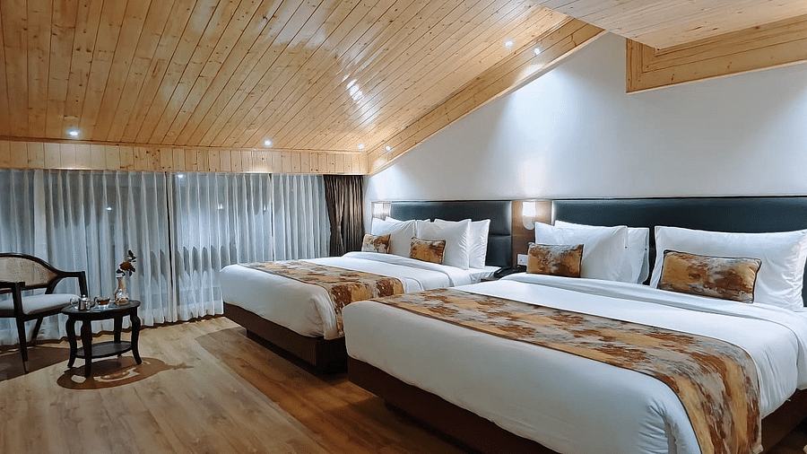 Hotel room with two beds, a side table, and a wood ceiling, offering a cosy and comfortable feel - Sumitel JB Park, Darjeeling