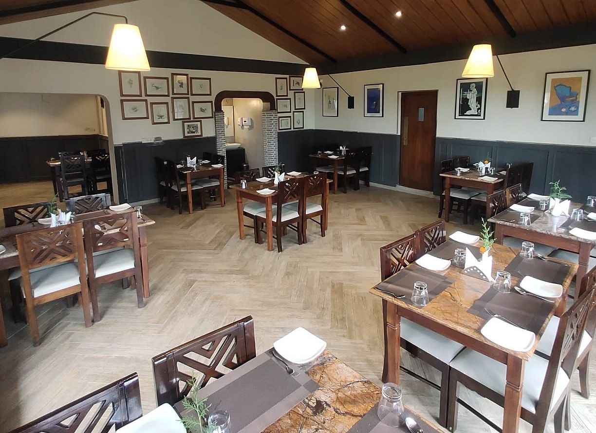Interior of a restaurant with wooden tables, chairs, and a high ceiling.
