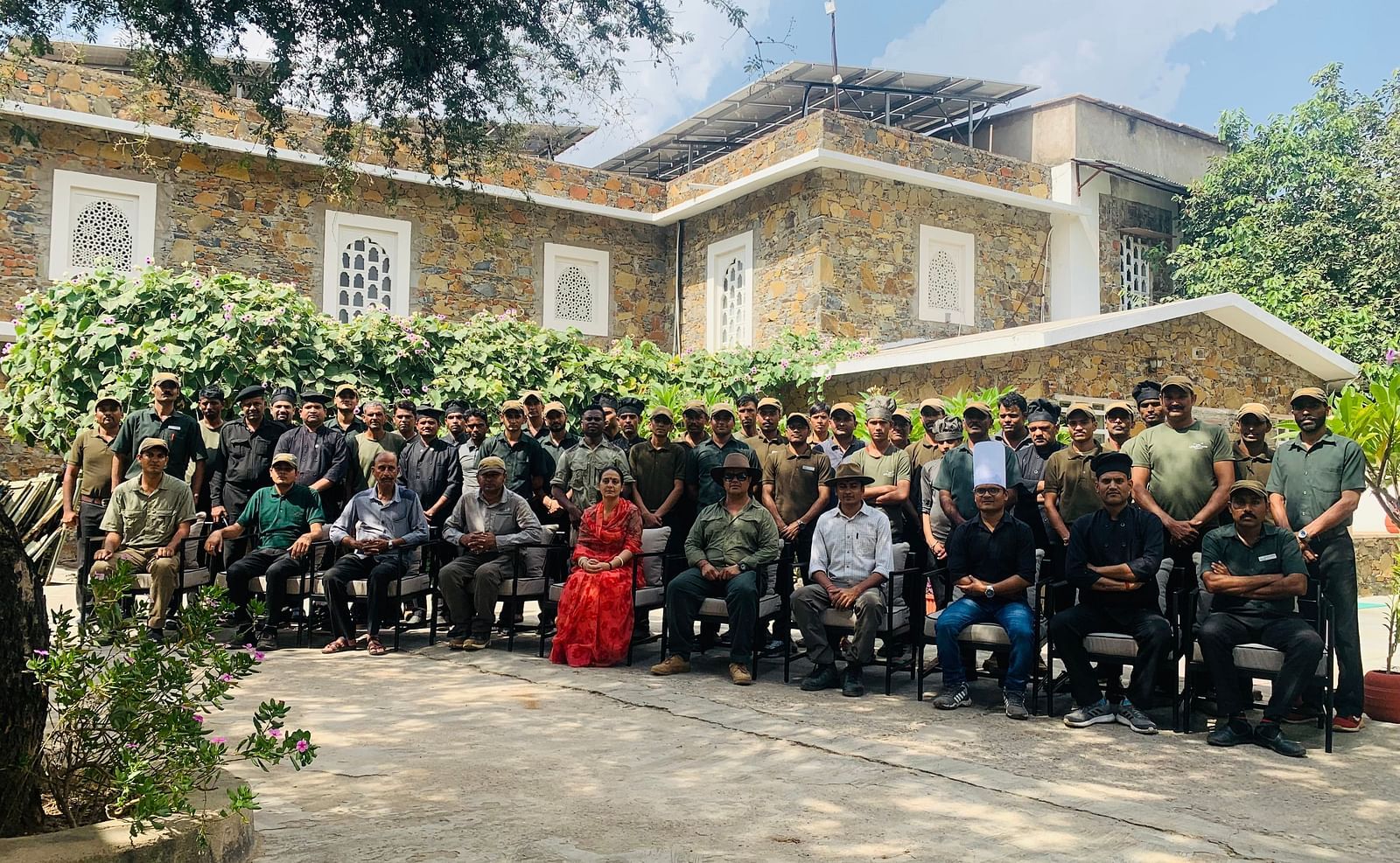 A large group of people posing together outside a stone building - Utsav Camp