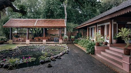 A facade of BluSalzz Villas - Muhamma Resort, Alleppey featuring the pond and the villa on the right and the restaurant in the background