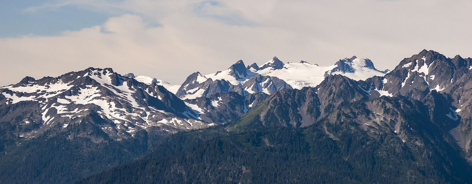 A panoramic view of a mountain landscape with clouds and colorful flags, showcasing a beautiful valley.