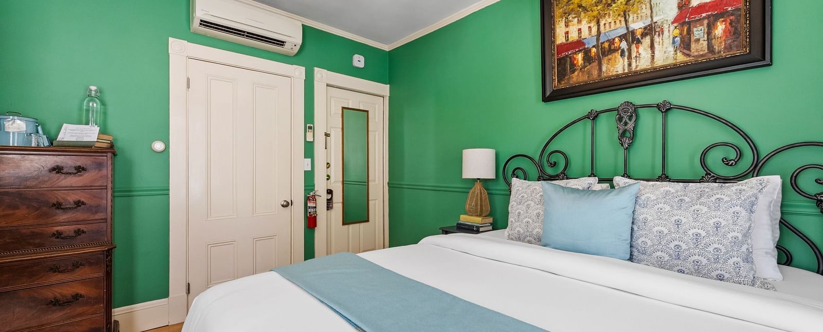 A bedroom with green walls, white bedding, and a decorative iron bed frame at Hartstone Inn