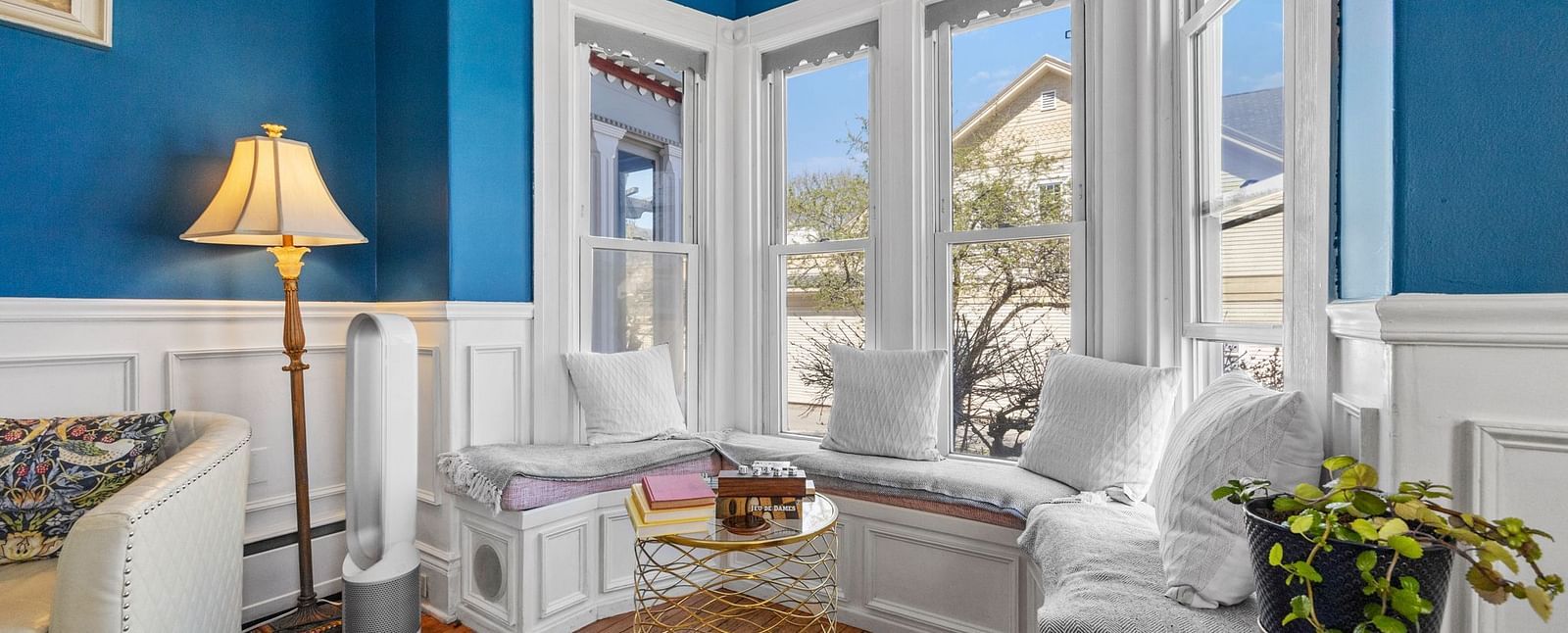 A window seating area at Hartstone Inn, featuring white furnishings, teal walls and fresh flowers