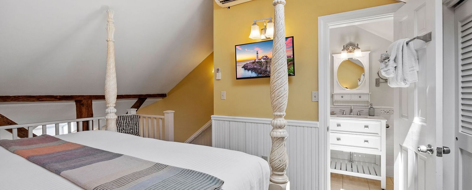 A room with double bed, Ac, tv and warm yellow accent walls at Hartstone Inn