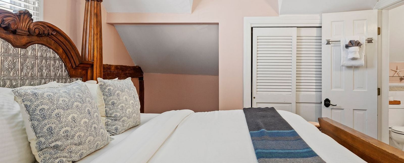 A bedroom with skylight, wicker headboard, and pastel walls at Hartstone Inn