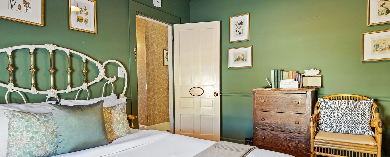 Green-themed bedroom with antique furniture and metal bed frame at Hartstone In