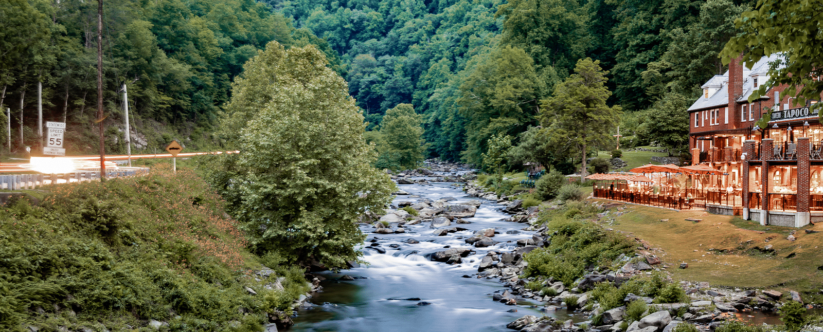 a beautiful river flowing over a rocky stream in front of the resort with a beautiful mountain vistas in the background - Historic Tapoco Lodge