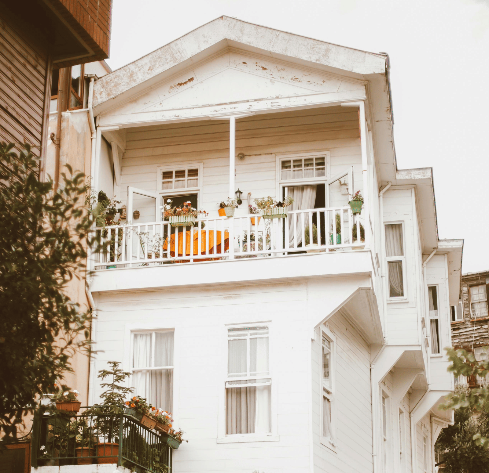 A tall, white residential building with multiple balconies is shown from a street-level perspective.