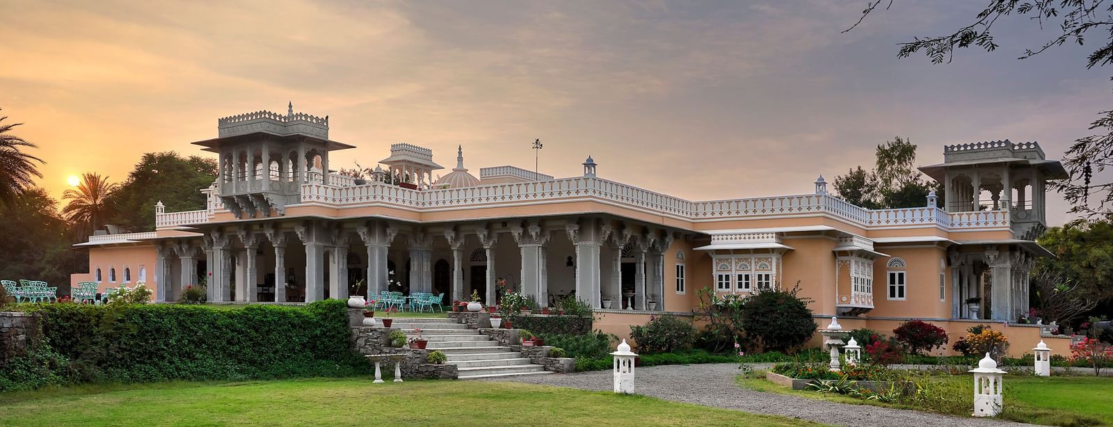 facade image of dev shree, deogarh with a beautiful lawn in the foreground and a picturesque sunset in the background