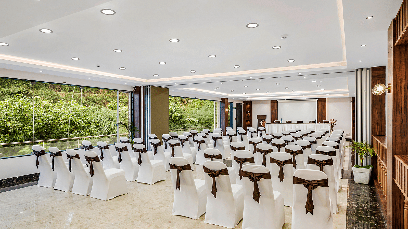 An image of a banquet space which is brightly lit with seating arrangement - GReaT Trails Kodaikanal By GRT Hotels
