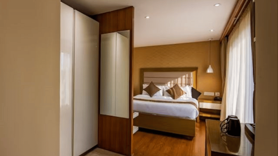 A hotel room featuring a plush bed, modern furnishing, and warm lighting seen through an open doorway at Yashshree The Imperial Inn, Siliguri