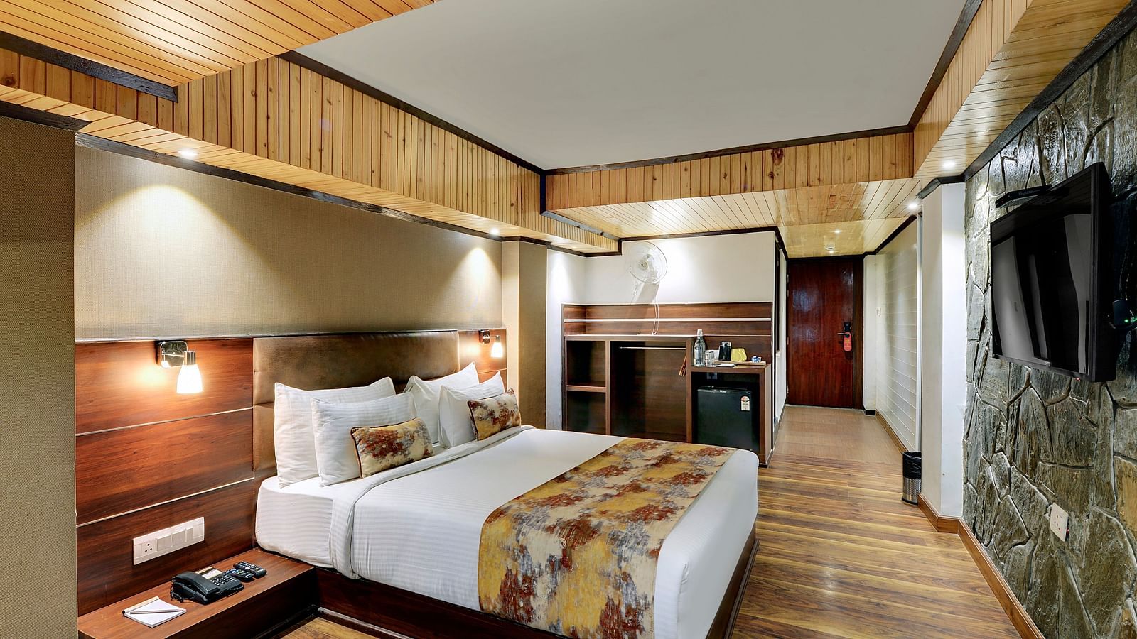 Image of a room with a bed, a television mounted on a stone wall at Yashshree Mall Road, Darjeeling.
