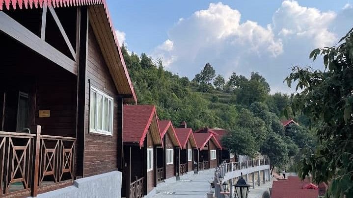 A scenic pathway winding between charming cottages with distinctive red roofs, showcasing the resort's picturesque setting - Digantaa Resort in Mukteshwar.