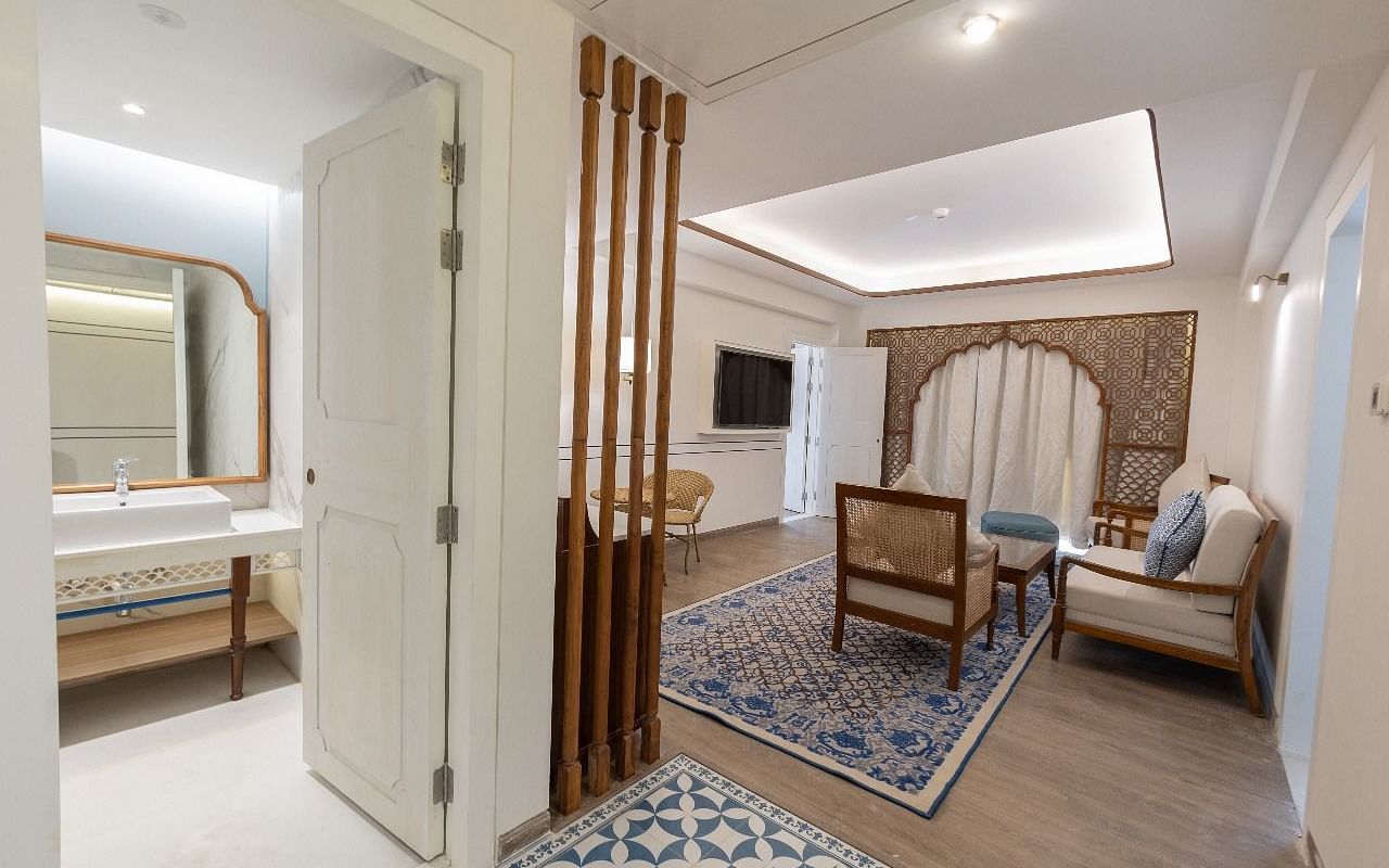 The living area at the Ananta with a door opening to the bathroom with a wide mirror inside it at Bhagirathi by RDB Atishay.