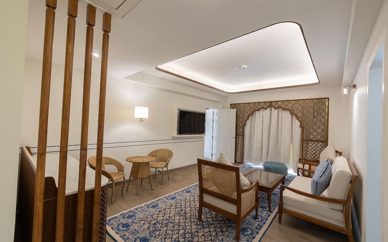 Corner view shot of the separate living area with a false ceiling and a comfortable couch set at Bhagirathi by RDB Atishay.