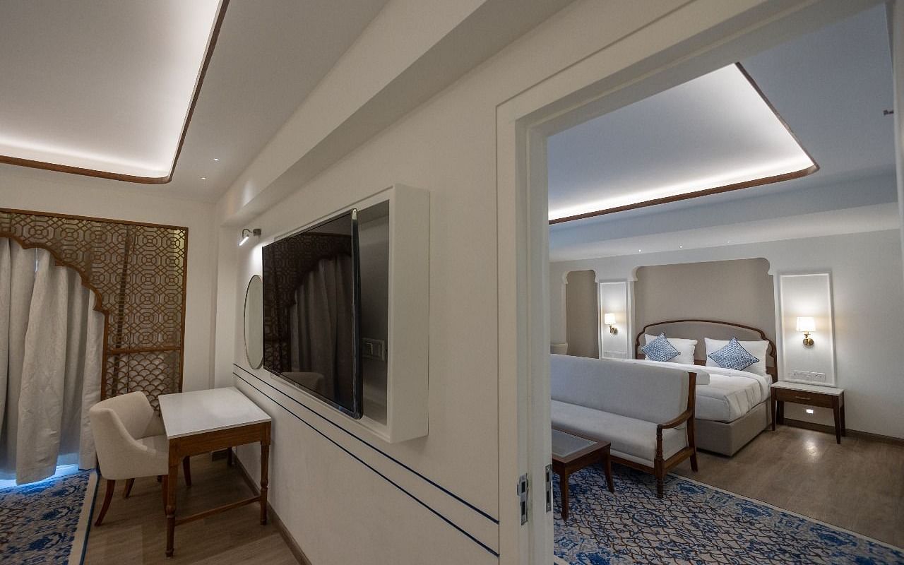 The Ananta Room showcasing a wall mounted television along with a doorway leading to the bedroom at Bhagirathi by RDB Atishay.