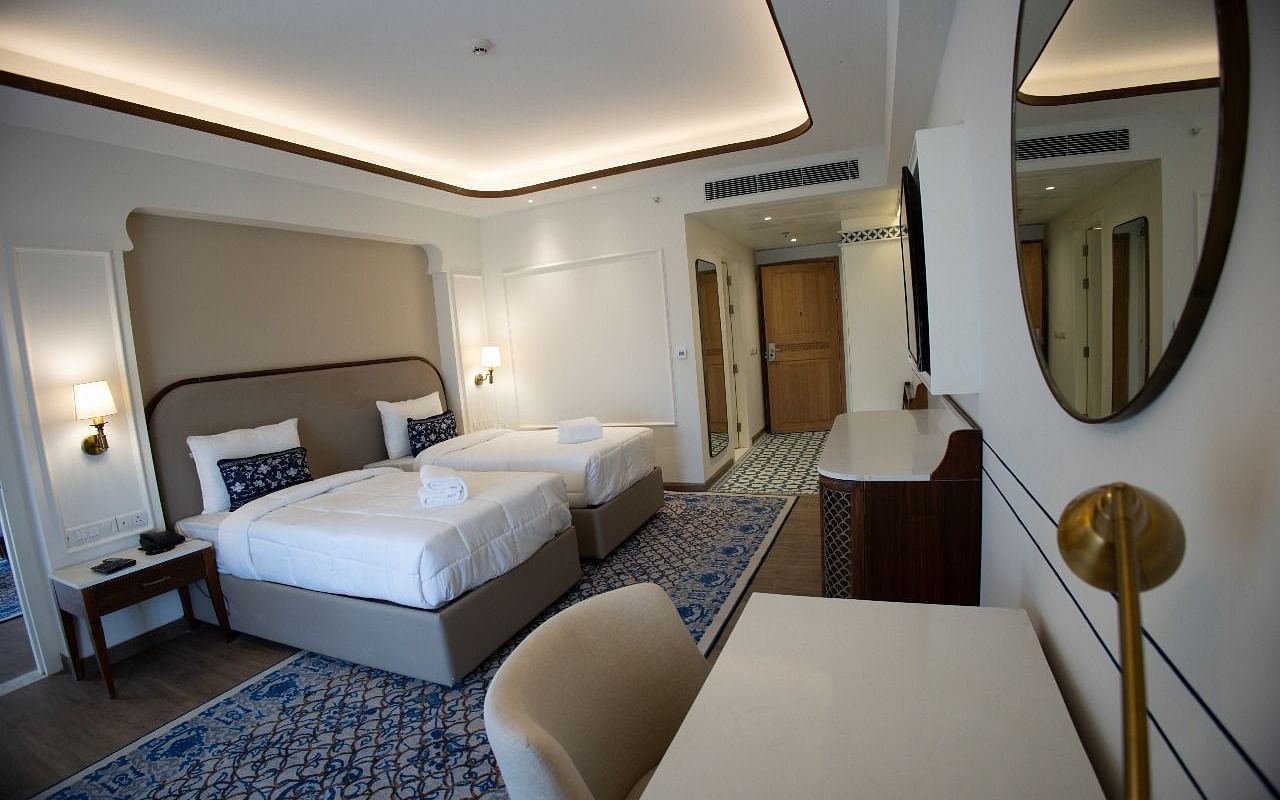 Full view shot of the Triveni Room with modern interiors along with two single beds in the room and bed side tables besides it at Bhagirathi by RDB Atishay.
