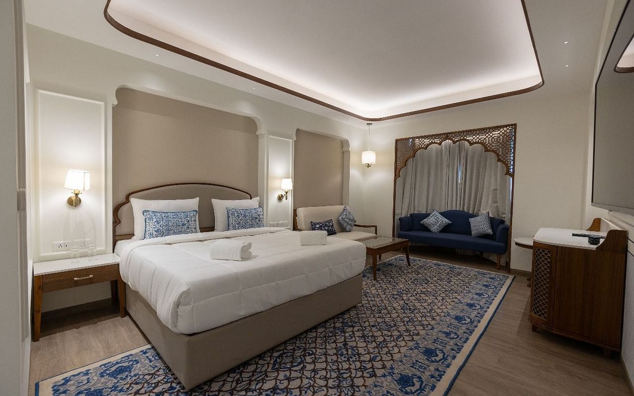 Corner view shot of the Mandakini Room featuring a plush double bed along with a long patterned carpet on the floor at Bhagirathi by RDB Atishay.